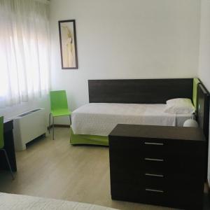 圣焦尔焦迪诺加罗Hotel Affittacamere alla Posta的一间卧室配有一张床、一张桌子和一把绿色椅子