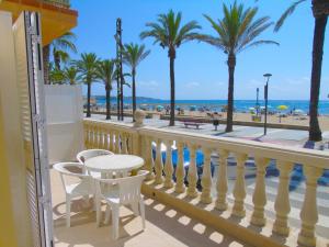 萨洛Apartamento Miramar的阳台配有桌椅,享有海滩美景。