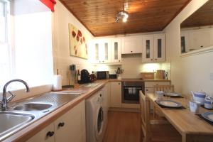 BirnamThe Wee Nook Birnam的厨房配有白色橱柜和木制天花板