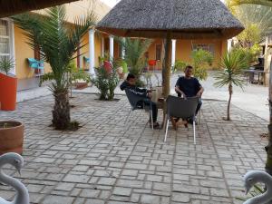 帕拉佩Bonjour Inn Palapye的两个男人坐在一个有天鹅的庭院的桌子上
