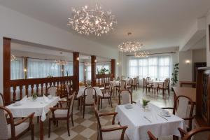 诺维斯莫克维克Villa Dr Szontagh Est. 1876的餐厅设有白色的桌椅和吊灯。