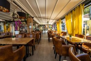 博尔马斯·莱斯·米默萨斯Hotel Restaurant Bellevue的餐厅设有木桌、椅子和黄色窗帘