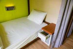 曼谷西亚梅子旅馆的一间小卧室,配有一张床和一张桌子