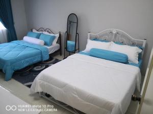 而连突Zumara Homestay Jerantut Pahang的一间卧室配有两张带蓝白色枕头的床