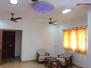 钦奈Swarna Sudarshan Service Apartment @ Adyar chennai的客厅配有两把椅子、一张桌子和吊灯。