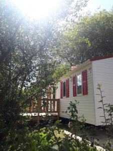 里瓦德塞利亚Camping Playa Sauces的一间白色的小房子,设有红色的窗户和门廊