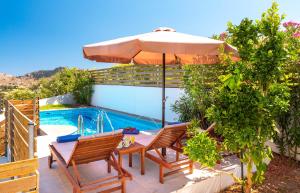 科林比亚Kolymbia Village的庭院设有带遮阳伞的桌子和游泳池。