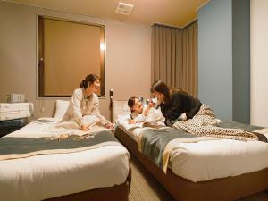 延冈市诺贝卡地区酒店 的两名妇女和一名儿童坐在房间里的床边