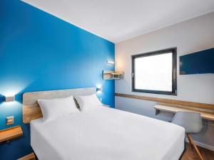 圣地亚哥ibis budget Santiago Providencia的卧室配有白色的床和蓝色的墙壁