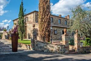 MontefollonicoPoggio Paradiso Resort & Spa的一座古老的石头房子,前面有一棵树