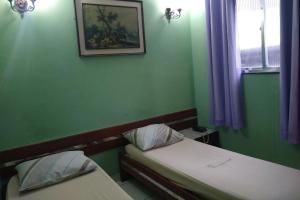 里约热内卢Hotel Barão De Tefé的绿色的客房设有两张床,墙上挂着一张照片