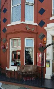 布莱克浦Grange House Hotel的前面有长凳的红色建筑