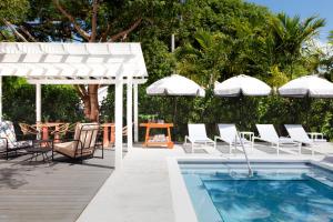 基韦斯特Ella's Cottages - Key West Historic Inns的一个带椅子、游泳池和遮阳伞的庭院