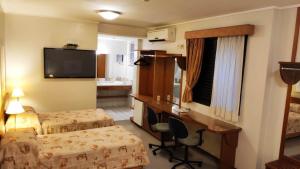 普雷图河畔圣若泽大都会酒店的酒店客房设有两张床、一张桌子和一台电视。