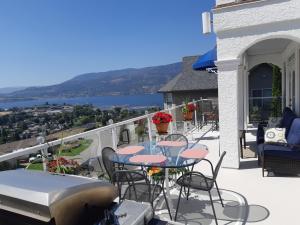 基洛纳Vacation Lake View House kelowna BNB的阳台配有桌椅和船只。