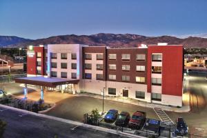 阿尔伯克基Holiday Inn Express & Suites - Albuquerque East, an IHG Hotel的一座大型建筑,前面有汽车停放