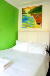 内罗毕Little Green Room Homestay near JKIA Airport & SGR Railway Station的卧室配有一张白色床,墙上挂有绘画作品