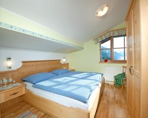 巴特霍夫加施泰因布兰德本哥特农家乐的一间卧室配有一张带蓝色枕头的床和一扇窗户。