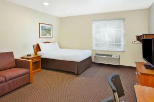圣查尔斯WoodSpring Suites St Louis St Charles的酒店客房配有床、沙发和电视。