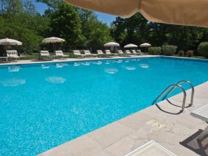 法扬斯红磨坊德拉坎曼多尔餐厅酒店的一个带椅子和遮阳伞的大型蓝色游泳池