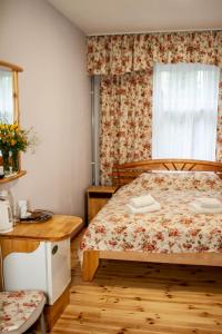 尤尔马拉日落酒店的一间卧室配有一张床、一张桌子和一个窗户。