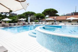 切尔维亚Hotel Conchiglia的一个带椅子和遮阳伞的大型游泳池