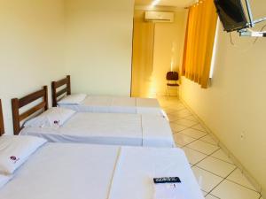 伊帕廷加Hotel Oliveira - By UP Hotel的一间设有三张床和电视的房间