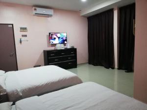 Kampong BembanHOTEL SAKIRAH的酒店客房设有两张床和一台平面电视。