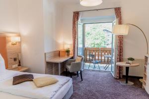 巴德哥依斯恩乌尔福赫格伊斯尔姆勒酒店的配有一张床、一张书桌和一扇窗户的酒店客房