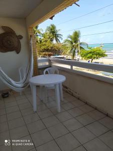 马拉戈日Mandala Hostel Maragogi Oficial的海滩阳台的白色桌椅