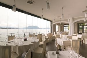 斯特雷萨贝唯酒店的餐厅设有白色的桌椅和大窗户。