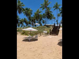 普拉亚多Apt Coral Azul Iberostate Praia do Forte的海滩上设有两把椅子和一把遮阳伞,还有楼梯