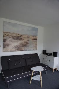 佩讷明德Maritim #1的客厅配有黑色沙发和绘画作品