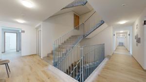 埃格勒Nonanteneuf Appart-hôtel - Aigle的房屋内的楼梯,拥有白色的墙壁和木地板