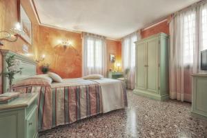 威尼斯菲兰其酒店的卧室配有一张床,墙上挂有绘画作品