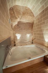 马泰拉Endea Suite Rooms & Lounge SPA的石墙客房内的浴缸