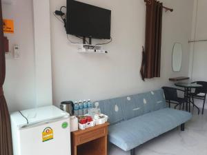 梭桃邑บ้านสวนนิสา的客房内的蓝色沙发、电视和冰箱