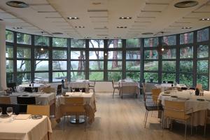 格拉诺列尔斯奥古斯塔巴塞罗那瓦莱斯酒店的餐厅设有白色的桌椅和大窗户。