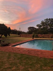 AvondzonAt The Rocks Country Estate的一座游泳池,位于一个享有日落美景的庭院内