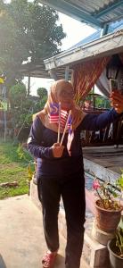 甲抛峇底Homestay Damai Sri Kota的佩戴美国国旗和牙刷的女人