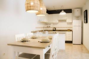 萨洛Domatsea Salou Mediterrani的白色的厨房配有桌子和白色冰箱