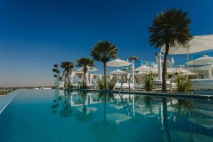 阿依纳帕Hotel Napa Suites (Adults Only)的一座拥有棕榈树和白色遮阳伞的游泳池