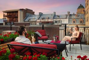 魁北克市奥特伊玛诺庄园酒店的坐在阳台上的男人和女人,喝一杯葡萄酒