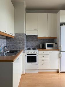科特卡Apartments ”Enkeli”的厨房配有白色橱柜和白色家电