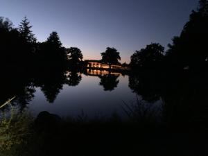 CleppéORANGERIE de CHATEL-Selection FIGARO & ELLE Magazine的享有湖泊的夜间美景,设有一座桥梁