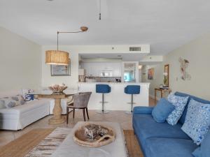 德斯坦Magnolia House at Destin Pointe III的一间带蓝色沙发的客厅和一间厨房