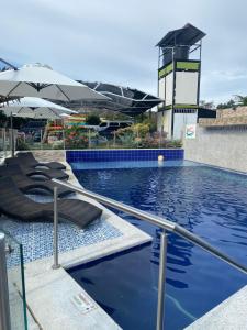 比利亚维哈HV Sueño Real Tatacoa的一个带2把躺椅和遮阳伞的游泳池