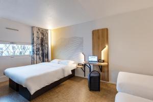 乌伊斯特勒昂B&B HOTEL Ouistreham的酒店客房配有一张床铺和一张书桌上的笔记本电脑