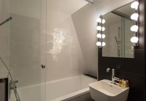 巴黎Hôtel La Parizienne的带淋浴、盥洗盆和镜子的浴室