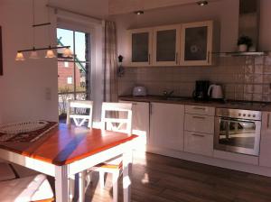 德兰斯克Haus Strandlaeufer的厨房配有白色橱柜和木桌
